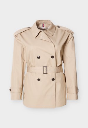 Bež plašč s preklopom z dvorednimi gumbi, ramenskimi stegni, pasom v pasu in gumbi na manšetah. Gladek tekstura, klasičen dizajn.