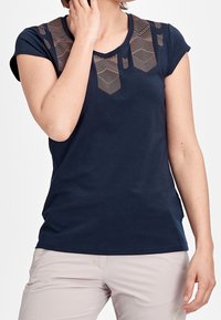 Marinblå t-shirt med korta ärmar och V-ringning, med ett geometriskt mönstrat meshnät på axlarna. Mjukt bomullsmaterial.