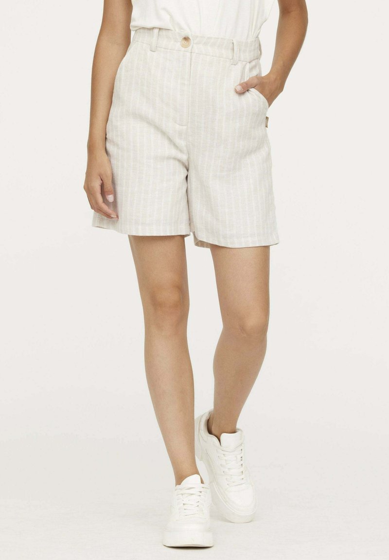 Shorts en lin de couleur claire ornés de rayures verticales, dotés d'une fermeture à bouton, de deux poches latérales et d'une coupe décontractée. Associés à des baskets blanches.