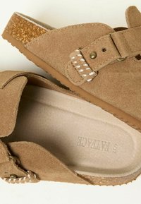 Brown suede sandal featuring a cork footbed, adjustable strap with metallic hardware, and white braided accent on the strap.
