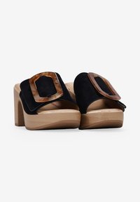 Sandalias de plataforma de ante negro con un chunky tacón de madera, que presentan acentos de carey sobredimensionados en la correa superior.