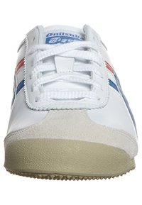 Sneaker bianco con strisce rosse e blu, lacci bianchi, punta in suede beige e suola beige testurizzata, mostrato frontalmente.