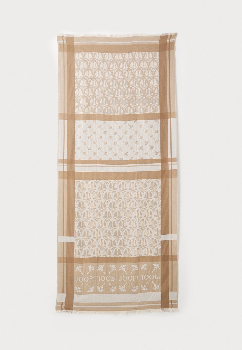 Cachecol bege estampado com designs geométricos e florais, apresentando uma textura suave e bordas em franjas. O texto do logo está integrado no padrão.