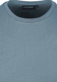 Blauwe korte mouwen crewneck t-shirt gemaakt van zacht katoen. Soepele textuur met een label waarop het merk "SUITABLE" en maat "M" staat.