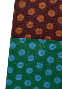 Dwa kawałki tkaniny: jeden bordowy z pomarańczowymi kropkowanymi wzorami przypominającymi plasterki cytrusów, a drugi zielony z niebieskimi kropkowanymi wzorami cytrusów.