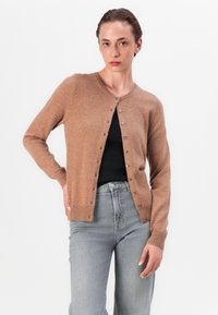 Hnědý pletený cardigan s kulatým výstřihem, dlouhými rukávy a zapínáním na knoflíky vpředu. Měkká textura a přiléhavý střih. Kombinováno se šedými džíny.