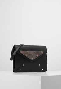 Borsa a tracolla in pelle nera con un pannello marrone testurizzato e borchie metalliche. Presenta una chiusura a patta e una tracolla regolabile per un uso a spalla.