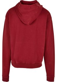 Felpa rossa con una vestibilità comoda, dotata di tasca a marsupio, polsini a costine e dettagli usurati su tutta la superficie. Materiale morbido in cotone misto.