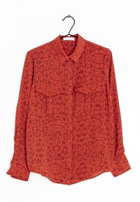 Chemise rouge à manches longues avec un motif serpent, dotée d'un col, de deux poches avant et de boutons aux manches. Confectionnée dans un tissu texturé.