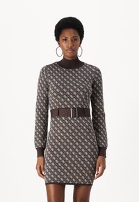 Kudotun bodycon elbise, kahverengi geometrik desen, uzun kollar, yüksek yaka ve parlak tokalı uyumlu bir kemer ile.