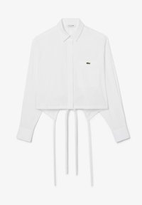 Camicia bianca corta con bottoni, maniche lunghe, colletto a punta, taschino sul petto e logo Lacoste verde. Presenta una cravatta regolabile all'orlo.
