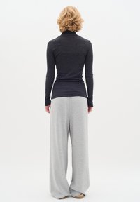 Dark gray long-sleeve top with a high collar paired with light gray wide-leg pants. Soft fabric texture, both items have a relaxed fit.