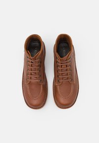 Scarpe in pelle marrone con punta arrotondata, cuciture beige in contrasto, lacci marroni e soletta imbottita. Progettate per un uso casual.