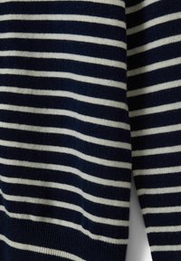 Sweter w granatowo-białe paski ma miękką strukturę z naprzemiennymi grubymi i cienkimi poziomymi paskami. Prosty krótki dekolt.