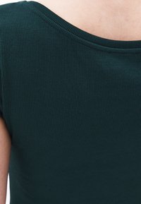 Tessuto rigato verde scuro con scollo delicato, caratterizzato da un design aderente e maniche corte, che mette in evidenza sottili dettagli di texture.