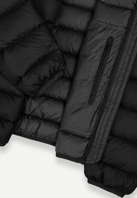 Giacca imbottita nera con design a trapunta, texture liscia, tasca con zip e polsini elasticizzati per una vestibilità aderente.