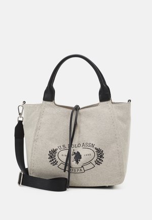 Canvas handtas in lichtbeige met zwarte leren accenten; heeft een logo graphic, dubbele handvatten en een verstelbare schouderriem.