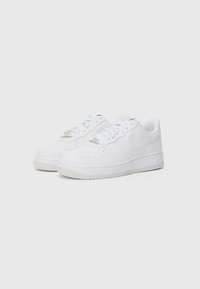 Sneakers in pelle bianca con design a bassa altezza, punta arrotondata, lati perforati, lacci piatti e suola in gomma testurizzata. Presentano un discreto dettaglio del marchio.