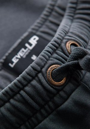 Grijze katoenen shorts hebben een rekbare tailleband met een verstelkoord, verfraaid met bronzen oogjes en een label met de tekst "LEVEL UP."