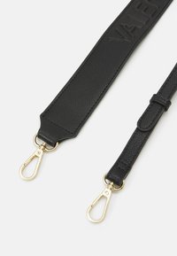 Svart texturerad väskrem med gyllene metalldragningshakar på en vit bakgrund, ena sidan bredare med prägling.