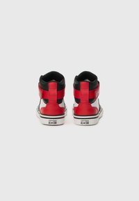 Korkealassa olevad spordijalatsid punasest nahast mustade aktsentidega, millel on kontrastne valge tald ja must sisemine vooder. nähtavad Converse All-Star brändi märgid.