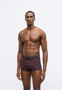 Férfi boxer rövidnadrág fekete alapszínnel, piros és fehér vízszintes csíkokkal, GANT logóval a derékrészen, testre szabott kialakítással és sima anyagtextúrával.