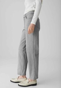 Jeans grigi con gamba dritta e una trama sottile, dotati di tasche laterali e di una vita classica, abbinati a mocassini beige.
