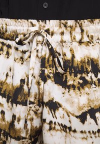Pantaloni leggeri con vita elastica, con una stampa astratta in nero, oro e bianco; presentano un laccio con dettagli dorati.