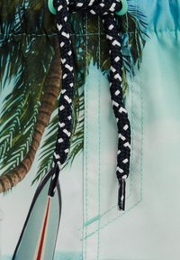 Világoskék, trópusi mintával díszített boardshort, pálmafákkal és szörfdeszkával. Fekete-fehér, műanyag végződésű fonott zsinór.