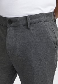 Gray trousers made of textured fabric, featuring a button closure, front pockets, and a tailored fit.