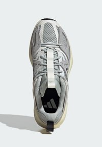 Grey athletic shoe featuring a mesh upper, thick sole, contrasting black accents, and a central pull tab, designed for comfort and support.