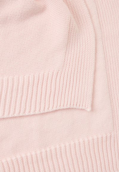 Μαλακό ροζ πλεκτό ύφασμα με διπλωμένες άκρες και λεπτομέρειες ριμπ υφής κατά μήκος του περιγράμματος, που αποκαλύπτουν τις υφές και τα μοτίβα υφαντουργίας.