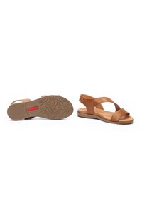 Sandalias de cuero marrón con correas cruzadas, diseño de talón abierto, suela de goma texturizada con patrones geométricos y plantilla acolchada.