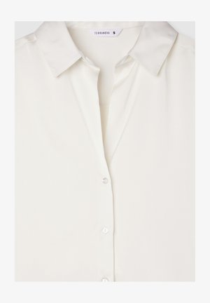 Blusa bianca leggera con colletto, chiusura frontale a bottoni e una consistenza liscia simile alla seta. L'etichetta del marchio è visibile.