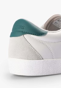Hvide sneakers med en struktureret grå ruskindsbag og en teal læderdetalje på hælen. Har en hvid gummisål med et mønstret design.