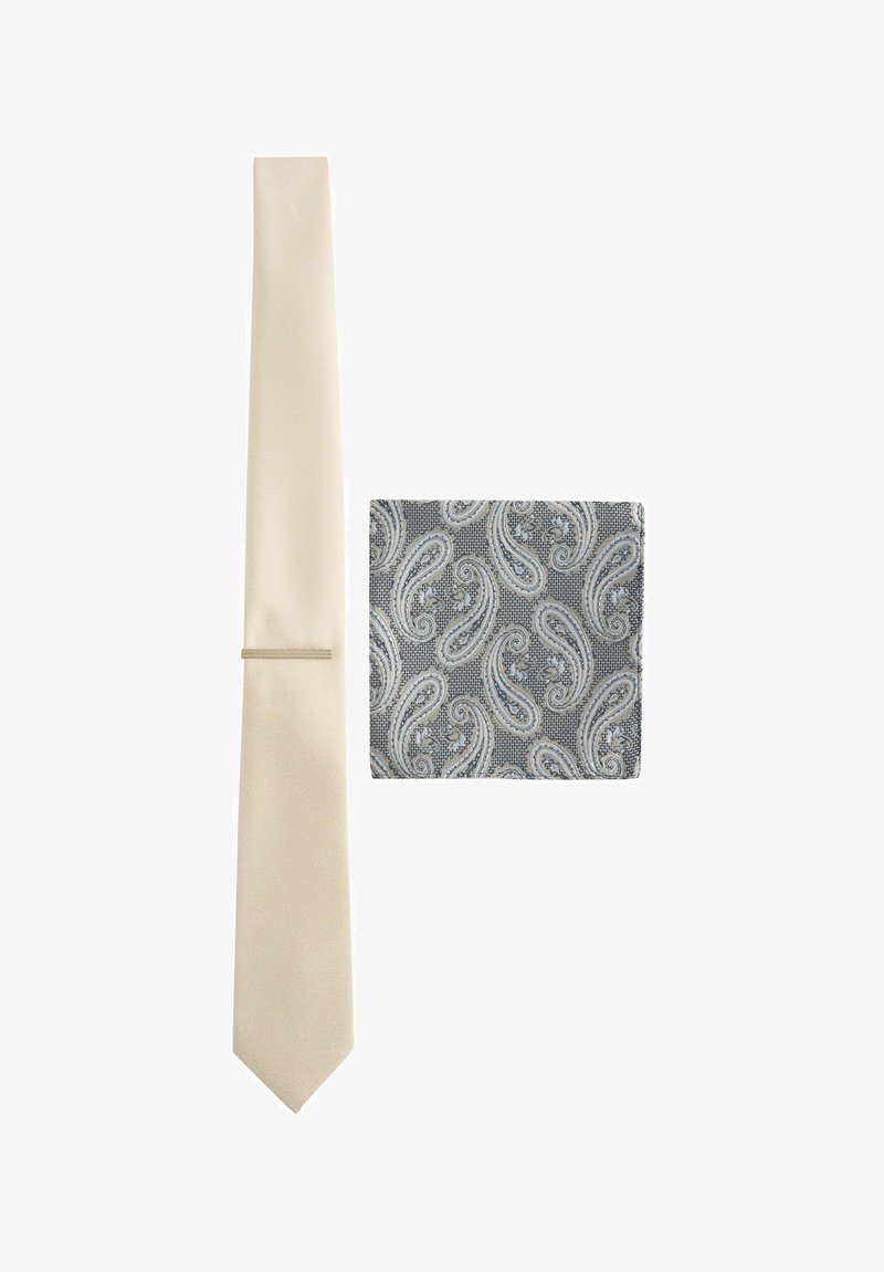 Cravate solide crème de largeur fine avec une finition texturée, accompagnée d'un pochette de costume gris à motif paisley avec des motifs blancs complexes.