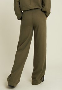 Pantalones de pierna ancha color verde oliva, hechos de tela suave, con cintura elástica y ajuste relajado, con mínimas costuras y sin patrones visibles.