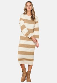 Abito a maniche lunghe in maglia con strisce alternate crema e beige, morbido al tatto e con una vestibilità rilassata, abbinato a stivali beige con lacci.