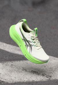 Chaussure de sport blanche avec une semelle et des accents verts vifs, ornée de rayures noires sur le côté et d'un embout texturé.