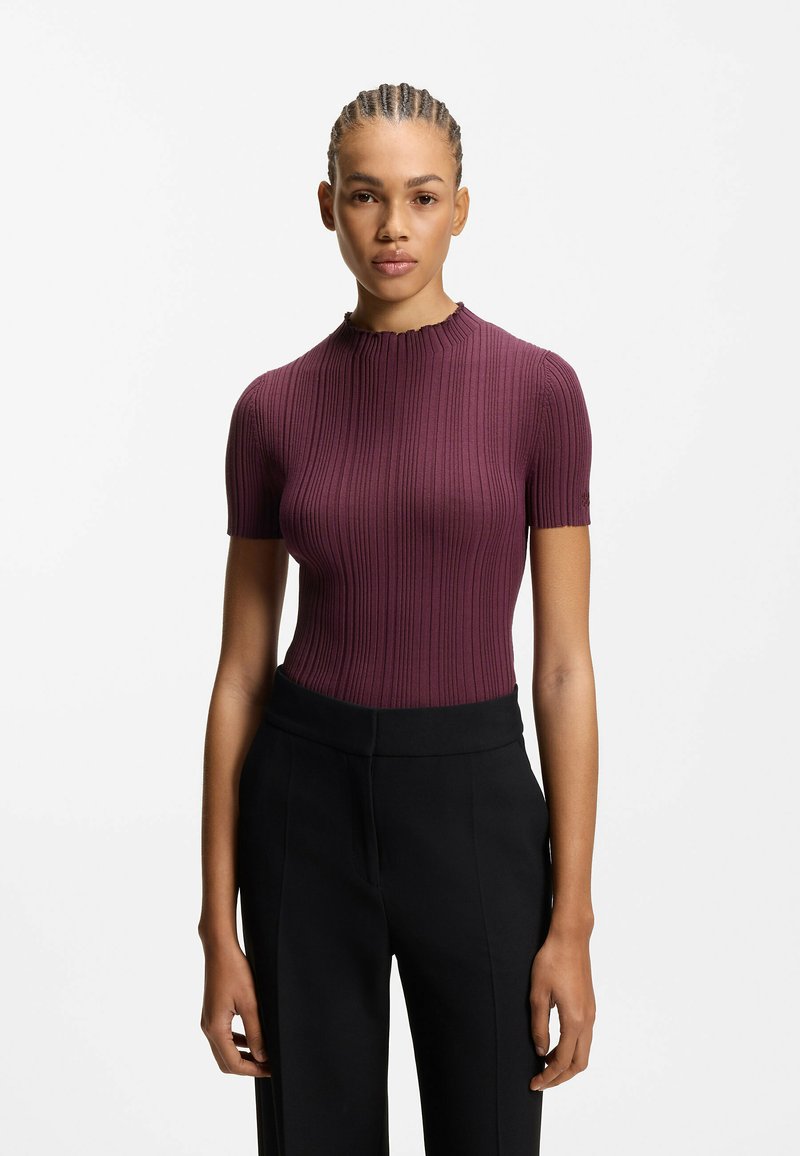 Bordowy prążkowany top z krótkim rękawem i wysokim dekoltem, zestawiony z czarnymi spodniami o szerokich nogawkach i gładkiej fakturze.