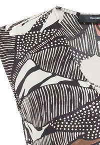 Tissu à motifs noir et blanc avec des textures variées, présentant des rayures, des pois et des formes abstraites. Conception en V avec des manches courtes.