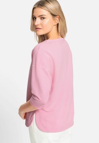 Leichtes, pink-weiß kariertes Oberteil mit Dreiviertelärmeln, abgerundetem Saum und seitlichen Schlitzen für mehr Bewegungsfreiheit. Weiche Textur.