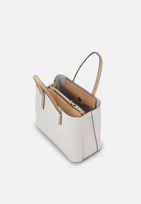Borsa a mano bianca in pelle con interno e manici color cammello, apertura superiore che mostra un vano centrale con zip e tasca con bottone a pressione all'interno.