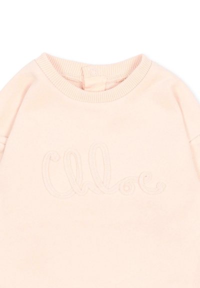 Chemise pour bébé rose pâle avec encolure ronde côtelée et inscription brodée « Chloé » à l'avant.