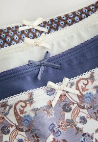 Quatre sous-vêtements féminins pliés avec de petits nœuds décoratifs, présentant des motifs unis, géométriques et floraux dans des tons bleus, blancs et marron.