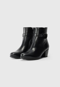 Bottines en cuir noir avec un bout arrondi, une fermeture éclair sur le côté, un bord supérieur courbé et un large talon. Elles sont dotées d'une sangle décorative et d'un matériel circulaire.