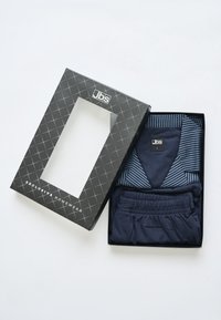 Conjunto de ropa de hogar azul marino en una caja negra con una ventana transparente. Incluye una parte superior a rayas y pantalones a juego, hechos de material suave.