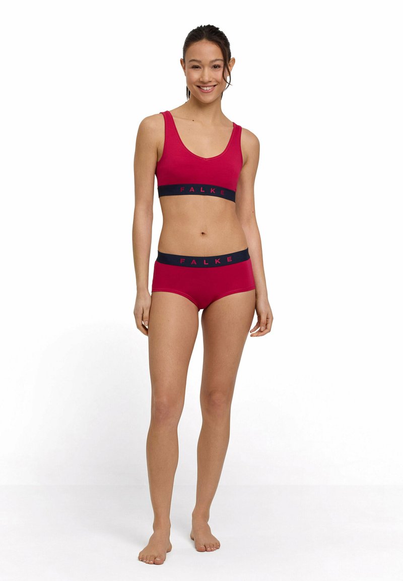 Red sports bra and matching boyshorts with navy elastic bands featuring "FALKE" logo. Smooth fabric with a fitted design and no patterns.