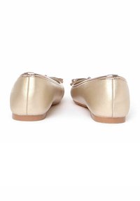 Bailarinas metálicas doradas con punta redondeada, acento de lazo en la parte delantera y una superficie lisa y brillante. Suela plana con tacón minimal.