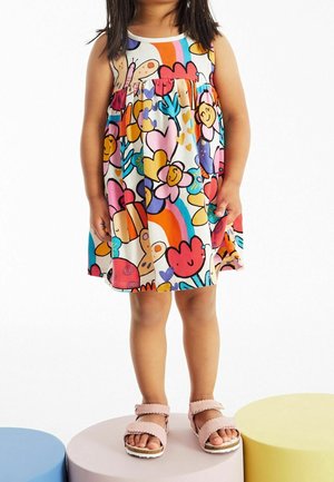 Robe colorée avec imprimé papillon et fleurs, design à étages et bordure blanche ; assortie à des sandales roses sur plateformes aux couleurs vives.